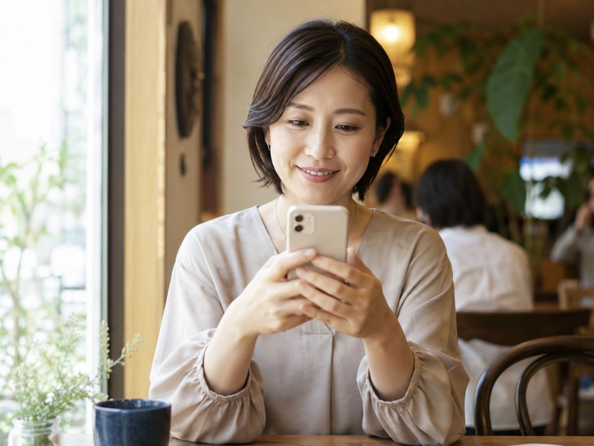 カフェでスマホからカウンセラーに相談する女性